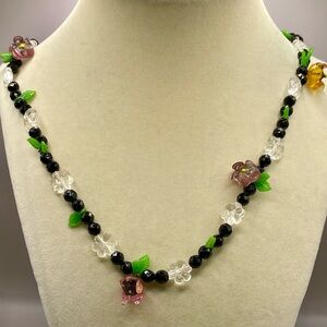 Handmade black beaded necklace with acrylic flowers and leaves. Silver tone.